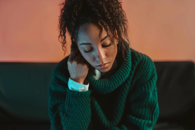 a woman in a green sweater sitting on a couch, a portrait, trending on pexels, hurufiyya, devastated, ashteroth, mid night, sitting on a table