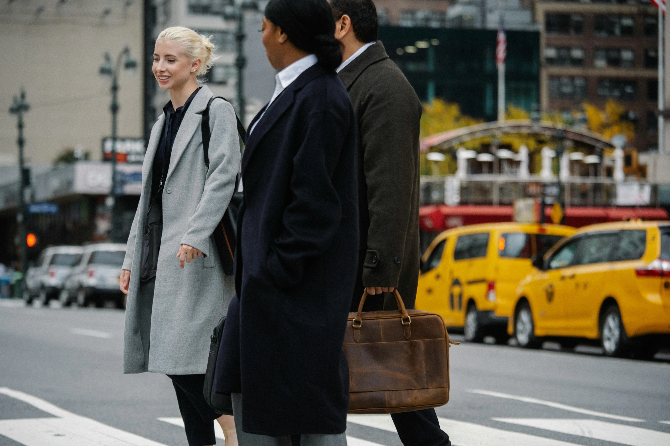 a couple of people that are standing in the street, trending on unsplash, walking to work with a briefcase, street of new york, light brown coat, cars and people