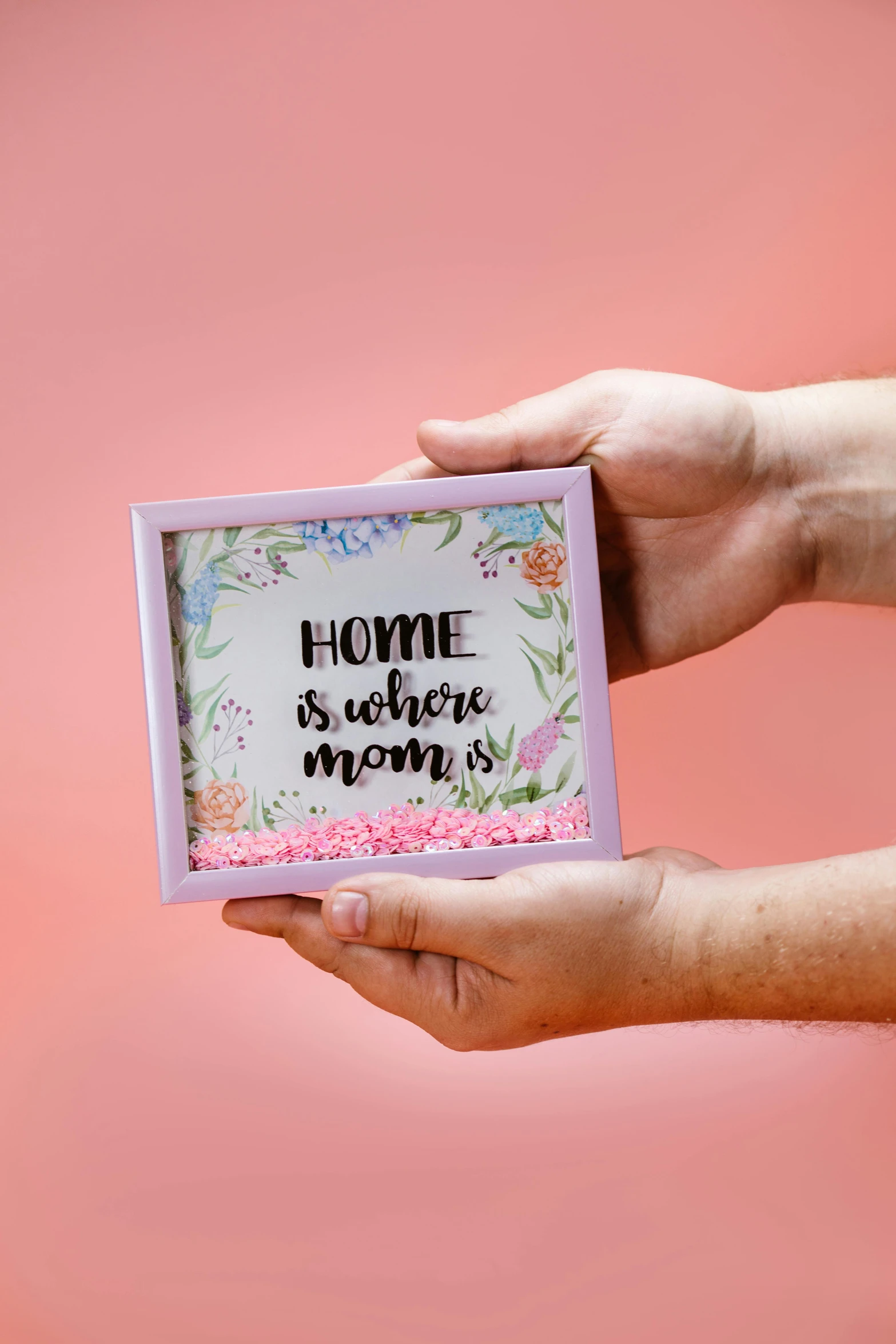 a person holding a card that says home is where mom is, a colorized photo, by Julia Pishtar, pexels contest winner, crayon art, 3d flat layered paper shadow box, pink petals, sprinkles, built on a small