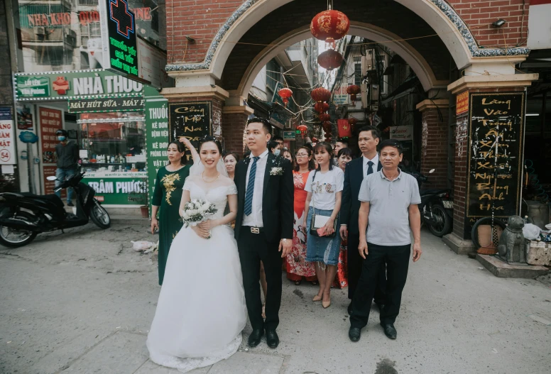 a group of people standing in front of a building, ao dai, standing in an alleyway, bride and groom, 15081959 21121991 01012000 4k