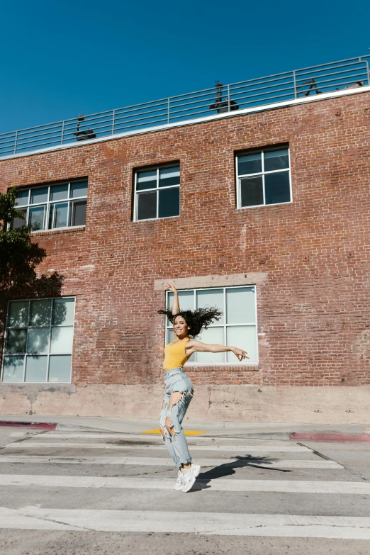 a woman jumping in the air in front of a building, :: madison beer, studio kai, brick building, justina blakeney