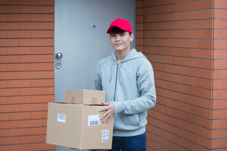 a man holding a box in front of a door, brown, portrait image, asian human, ecommerce photograph