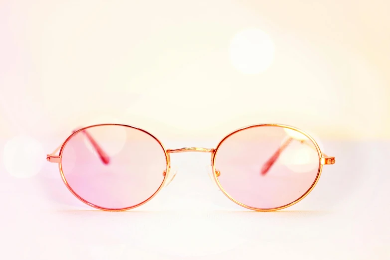 a pair of sunglasses sitting on top of a table, by Nicolette Macnamara, pexels, pink and gold, red rim light, 90s photo, high - key