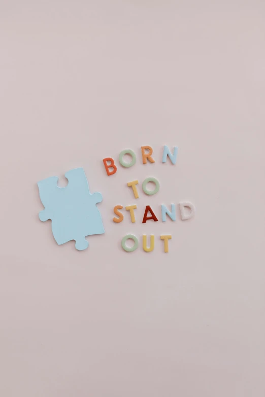 a puzzle piece with the words born to stand out, featured on instagram, society 6, press shot, paper cutouts of plain colors, back - shot