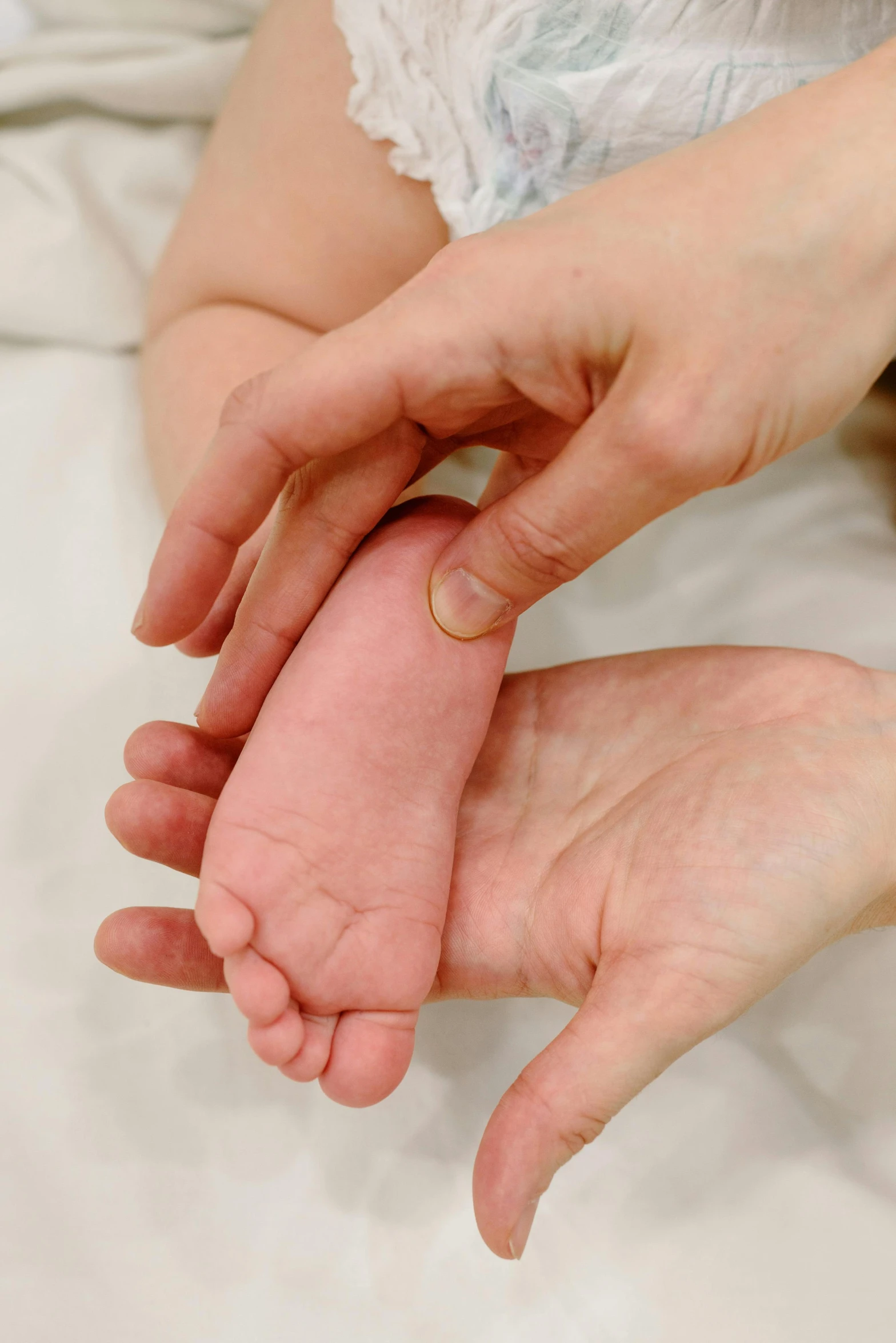 a close up of a person holding a baby's foot, corrected hands, soft volume absorbation, uploaded, small