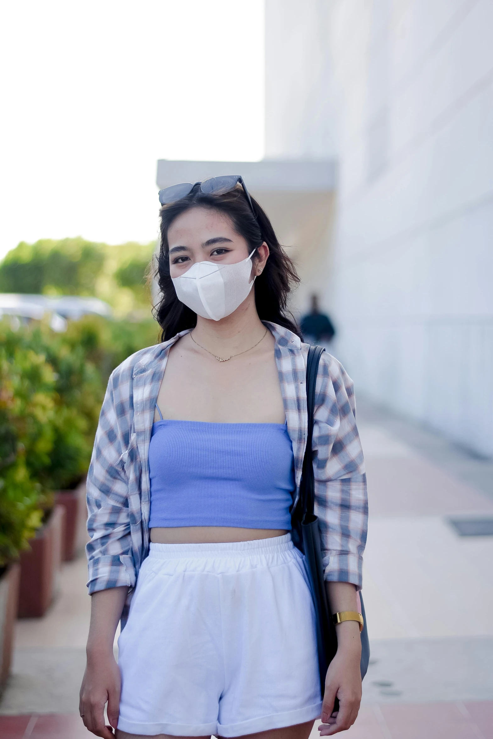 a woman wearing a face mask standing on a sidewalk, by helen huang, trending on pexels, white skirt and barechest, wearing a light blue shirt, croptop, at netflix