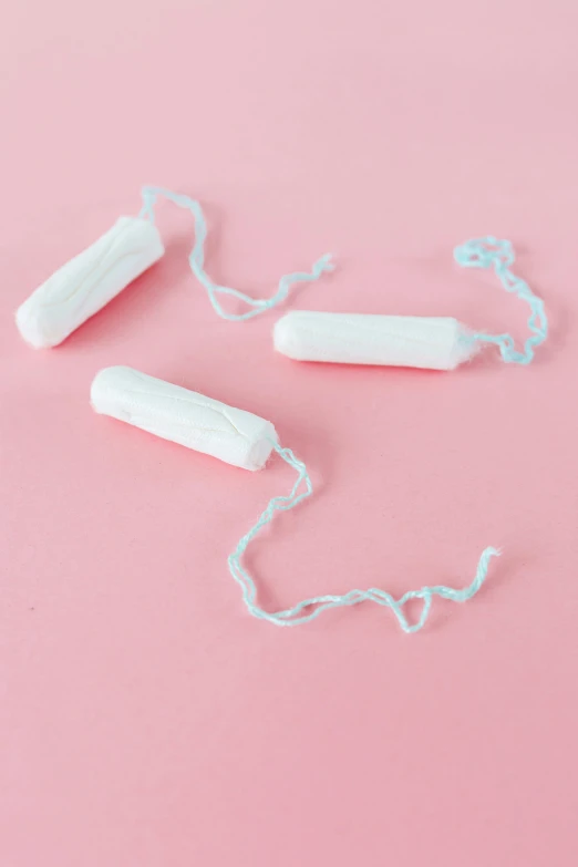 a couple of toothbrushes sitting on top of a pink surface, bandoliers, entangled vibrating, white ribbon, vines