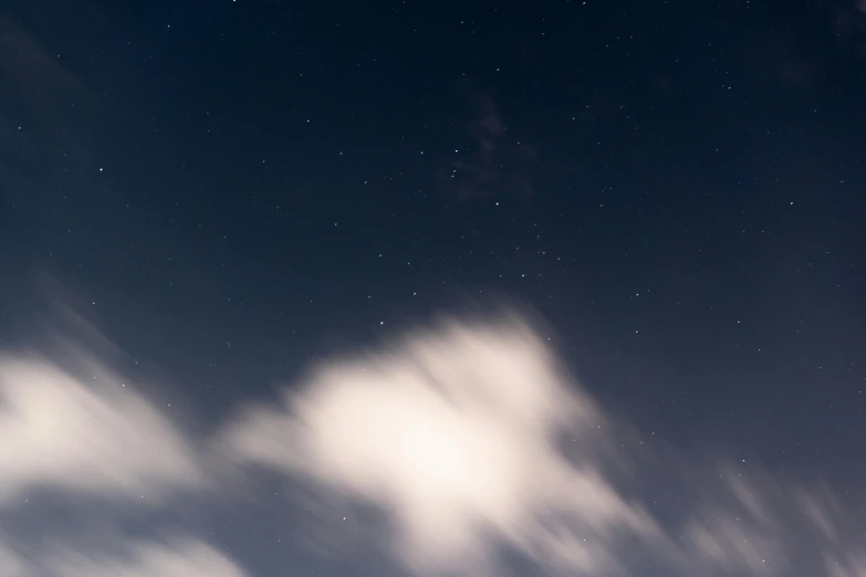 a man riding a snowboard on top of a snow covered slope, an album cover, pexels contest winner, light and space, night sky with clouds and stars, long exposure 8 k, aesthetic clouds in the sky, tiny stars