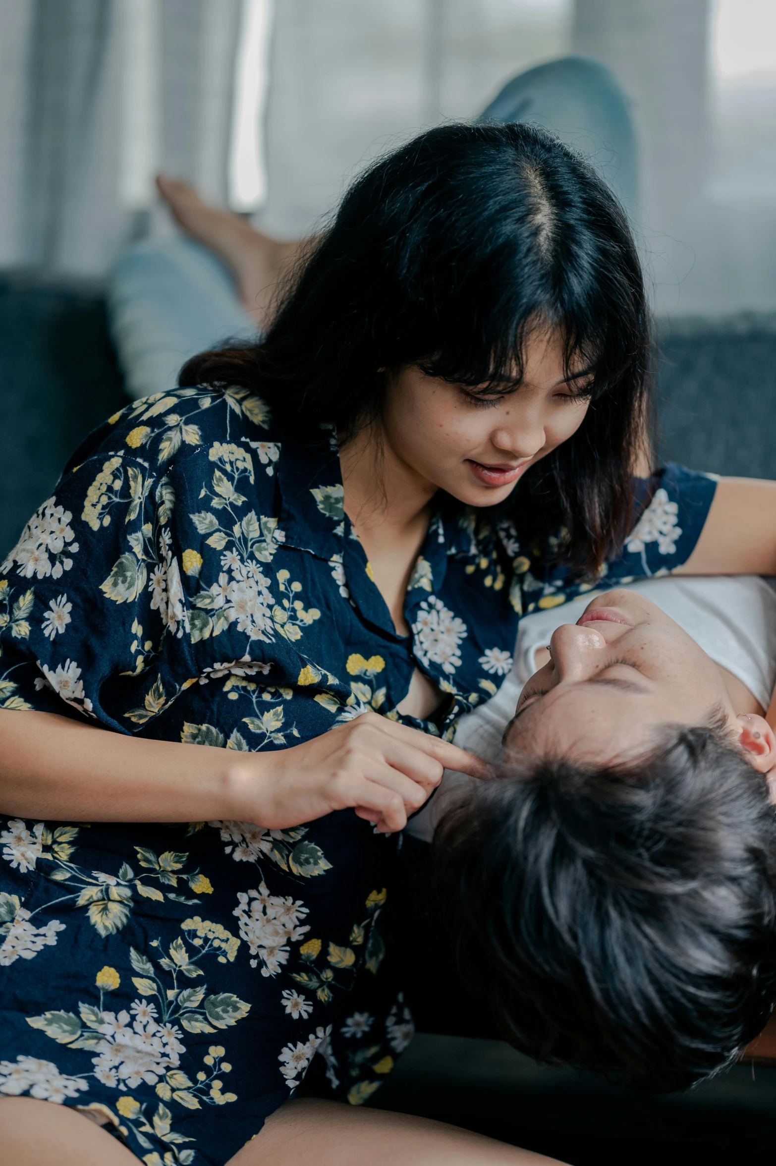 a woman sitting on top of a couch next to a man, pexels contest winner, renaissance, asian female, nursing, pleasing, wearing pajamas