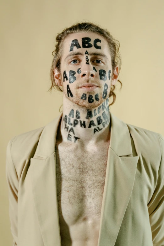 a man with letters painted on his face, a tattoo, by Jessie Alexandra Dick, beth cavener, slide show, adam ondra, promotional image