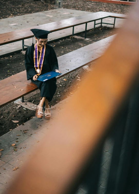 a woman in a graduation gown sitting on a bench, trending on unsplash, academic art, multiple stories, sitting on the ground, sitting on a mocha-colored table, photographed for reuters