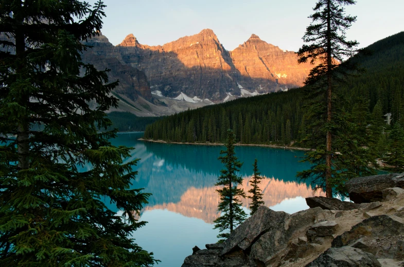 a large body of water surrounded by trees, a photo, by George Abe, pexels contest winner, hurufiyya, banff national park, beautiful late afternoon, craggy mountains, conde nast traveler photo