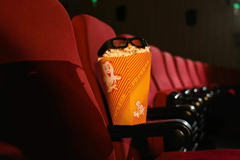 a popcorn cup sitting on top of a red chair, full body shot of duke nukem 3d, in a cinema, close up to the screen, youtube thumbnail