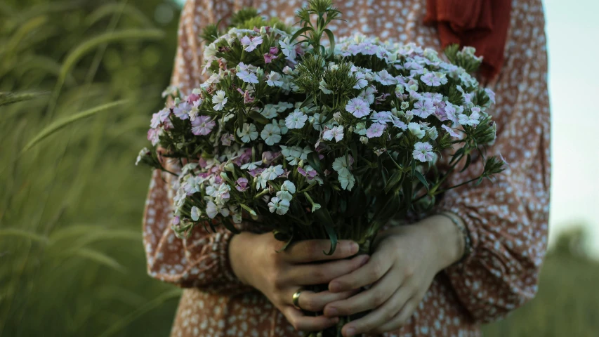 a woman holding a bunch of flowers in her hands, inspired by Elsa Bleda, unsplash, verbena, delicate patterned, edible flowers, pinks