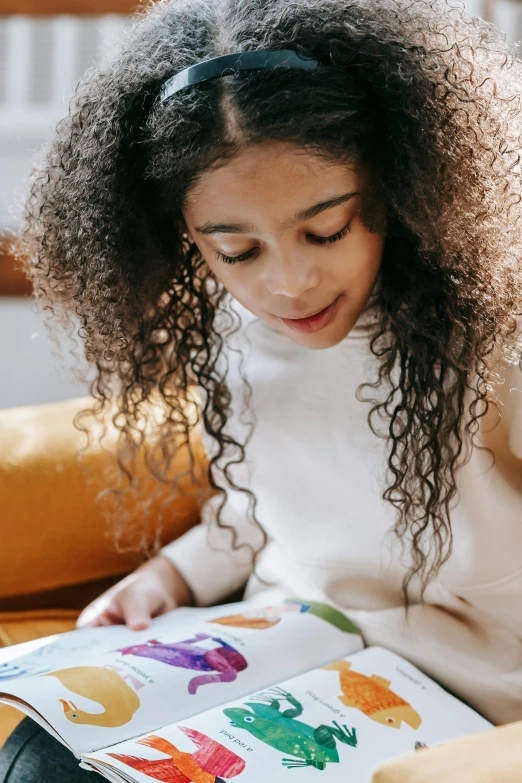 a little girl sitting on a couch reading a book, a child's drawing, pexels contest winner, curls, light skinned african young girl, gif, medium close up