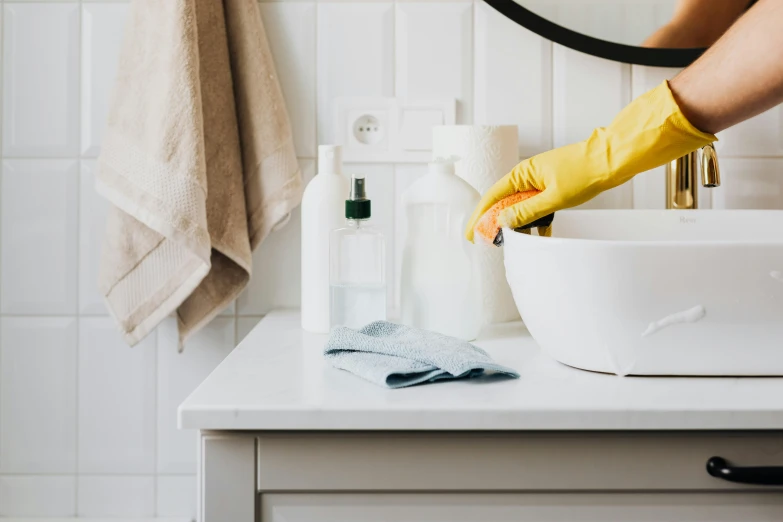 a person in yellow rubber gloves cleaning a bathroom sink, pexels contest winner, white marble interior photograph, fan favorite, background image, watering can