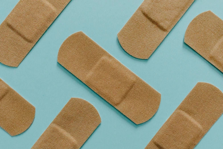 a group of adhesives on a blue surface, trending on pexels, bandages, wearing a brown, soft shade, in a row