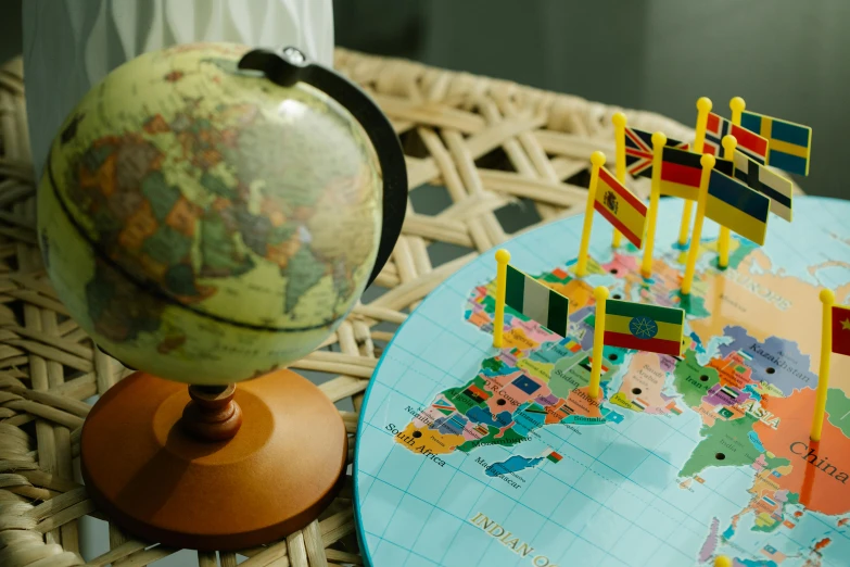 a map sitting on top of a table next to a globe, flags, wooden art toys, private school, high quality upload