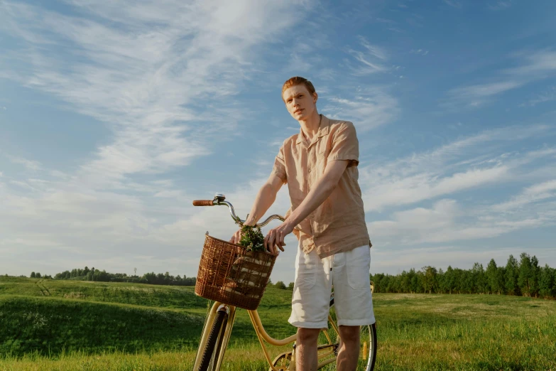 a man standing next to a bicycle in a field, pexels contest winner, wearing a linen shirt, avatar image, pale skin, wearing shorts and t shirt