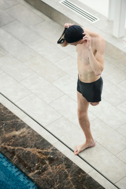 a man standing on the edge of a swimming pool, by Jan Tengnagel, happening, shy looking down, helmet is off, high quality photo, alex kanevsky