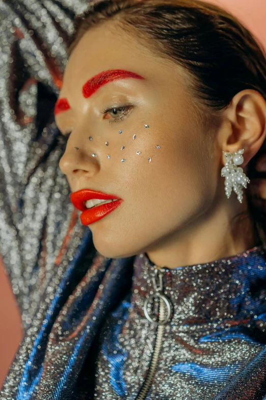 a close up of a woman with glitter on her face, an album cover, by Julia Pishtar, trending on pexels, maximalism, long earrings, bright red lipstick, silver accessories, 3/4 view from below