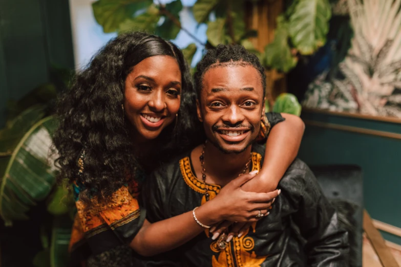 a man and a woman sitting next to each other, an album cover, pexels contest winner, hurufiyya, both smiling for the camera, half african, embracing, thumbnail