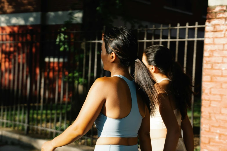 a couple of women walking down a street, trending on pexels, detailed sports bra, afternoon sunlight, profile image, thumbnail