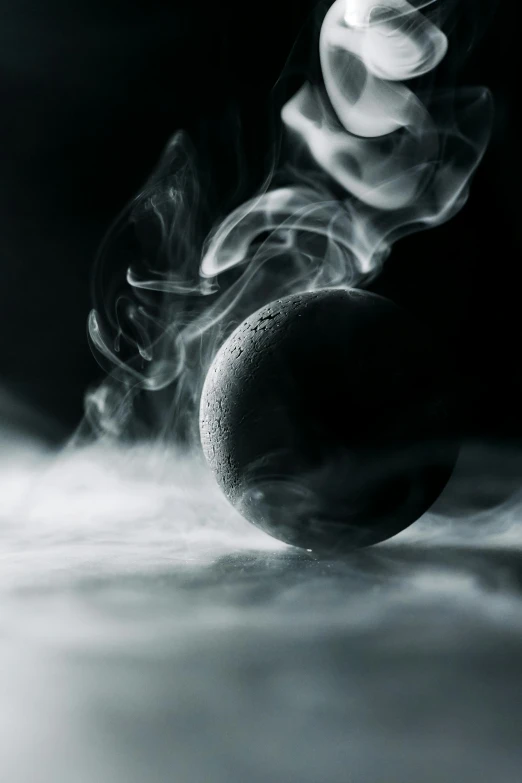 a black and white photo of a ball with smoke coming out of it, moonscape, dark-toned product photos, incense, cold mood