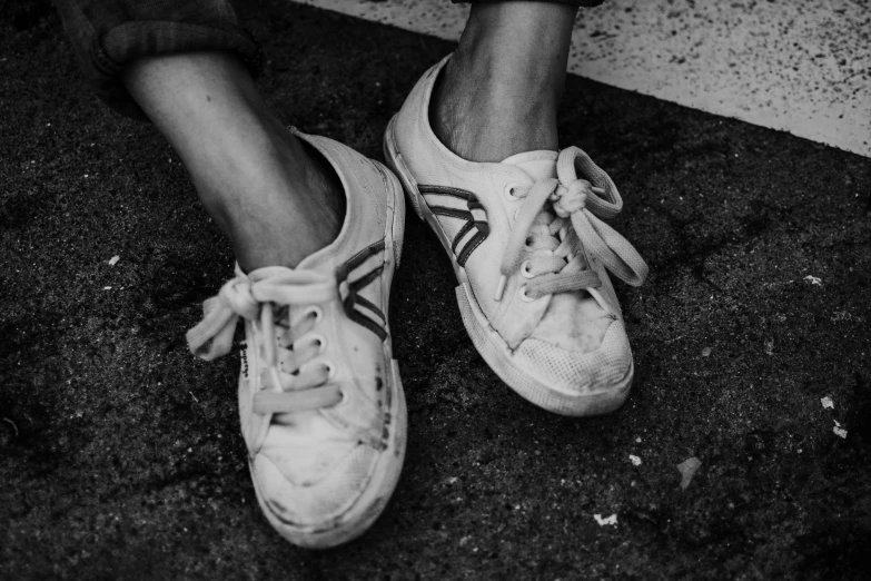 a black and white photo of a person's shoes, wearing white sneakers, dilapidated look, lowres, karen vikke