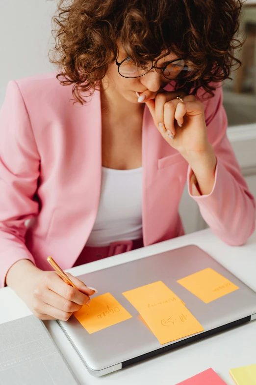 a woman sitting in front of a laptop with sticky notes on it, pale orange colors, thumbnail, functional and elegant look, professional image