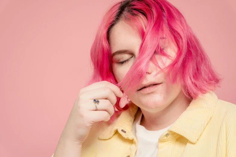 a woman with pink hair wearing a yellow shirt, an album cover, inspired by Elsa Bleda, trending on pexels, point finger with ring on it, ((pink)), 8k 50mm iso 10, pale - white skin