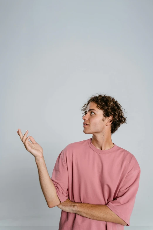 a man with curly hair wearing a pink shirt, trending on pexels, happening, indistinct man with his hand up, minimalist photo, calmly conversing 8k, up there