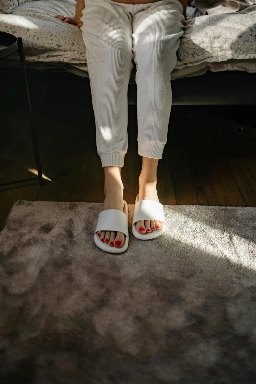 a woman sitting on a bed reading a book, by Julia Pishtar, trending on unsplash, minimalism, slippers, white puffy outfit, 15081959 21121991 01012000 4k, stand on stone floor