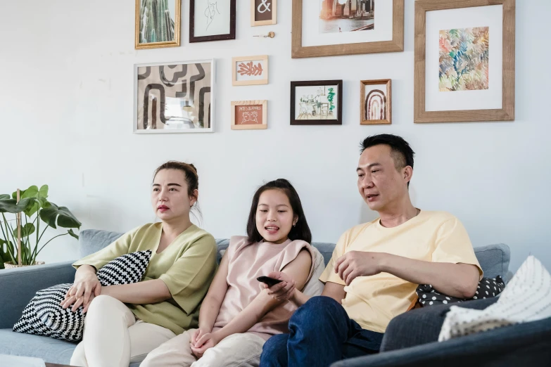 a group of people sitting on top of a couch, inspired by Zhang Xiaogang, pexels, portrait of family of three, watching tv, promotional image, background image