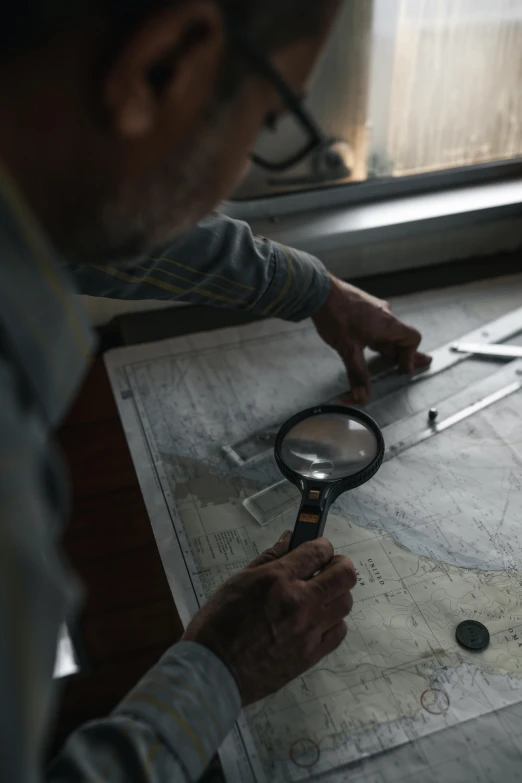 a man looking at a map with a magnifying glass, unsplash, visual art, boat, still from film, multiple stories, high angle