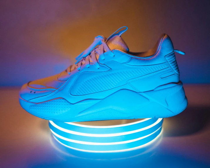 a pair of blue sneakers sitting on top of a table, a hologram, pexels contest winner, figuration libre, blue and orange rim lights, puma, triple white colorway, flume