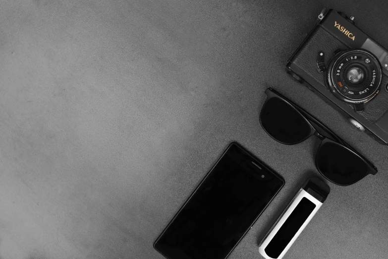 a black and white photo of a camera, sunglasses, and a cell phone, minimalism, 8k)), all black matte product, black floor, cop