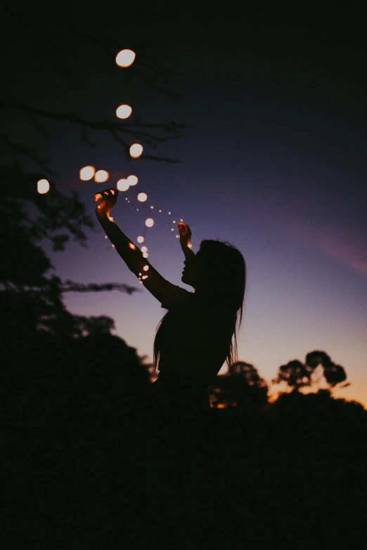 a woman standing on top of a lush green field, a picture, pexels contest winner, light and space, floating lights, silhouette :7, bubbles in the air, string lights