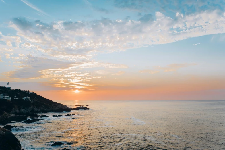 the sun is setting over a body of water, pexels contest winner, turquoise horizon, cliffside, pastel sky, conde nast traveler photo