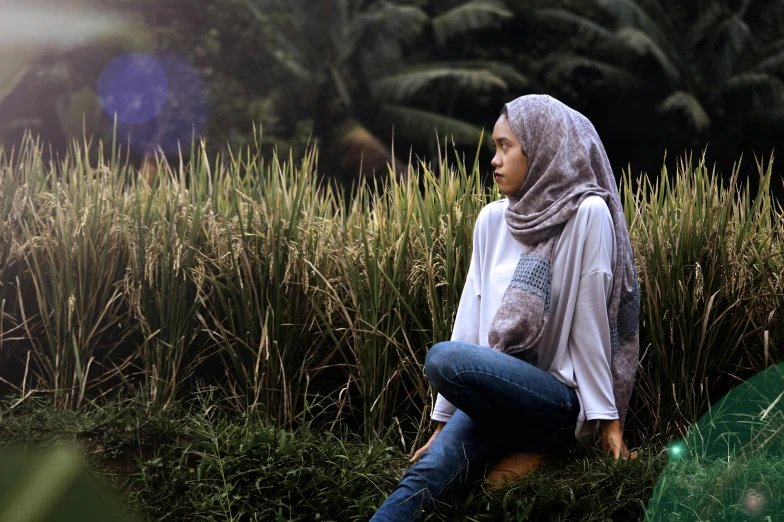 a woman sitting in a field of tall grass, a picture, unsplash, hurufiyya, malaysian, portrait image