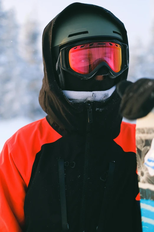 a man standing in the snow holding a snowboard, pexels contest winner, dark visor covering top of face, red - black, orange balaclava, wearing black frame glasses