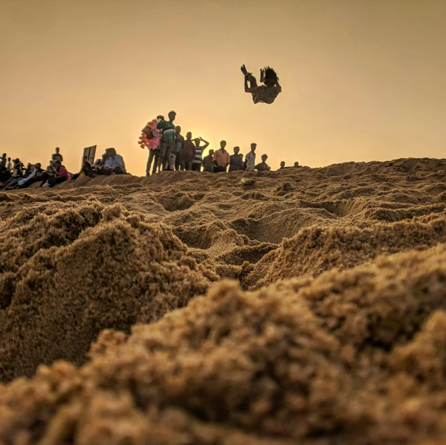 a man flying through the air while riding a dirt bike, an album cover, pexels contest winner, crowded beach, islamic, festivals, candid photography