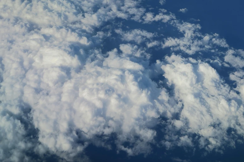 a jetliner flying through a cloudy blue sky, an album cover, unsplash, hurufiyya, layered stratocumulus clouds, taken from orbit, today\'s featured photograph 4k, low angle 8k hd nature photo