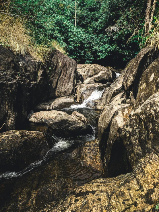 a river running through a lush green forest, an album cover, unsplash, sri lankan landscape, rocky terrain, low quality photo, boulders