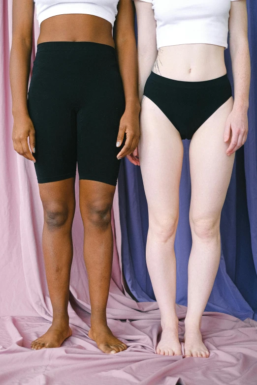 a couple of women standing next to each other, inspired by Vanessa Beecroft, trending on pexels, renaissance, black boy shorts, crop yoga short, thumbnail, light and dark