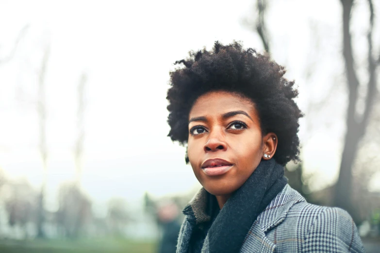 a close up of a person wearing a jacket and scarf, by Lucia Peka, pexels contest winner, natural hair, looking off into the distance, kara walker, a woman walking