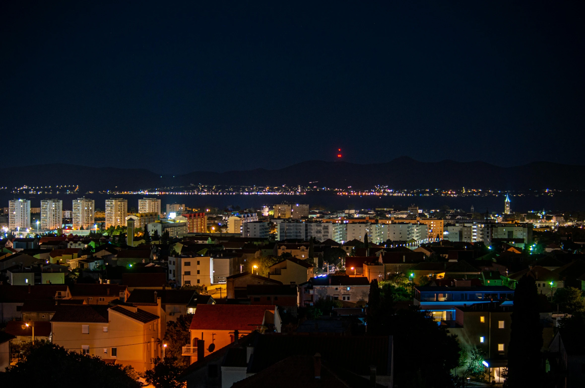 a view of a city at night from the top of a hill, by Mathias Kollros, pexels contest winner, split lighting, distant mountains lights photo, slide show, 8k octan photo