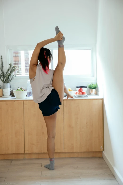 a woman doing a yoga pose in a kitchen, pexels contest winner, arabesque, in shorts, long ponytail, scientific photo, corner