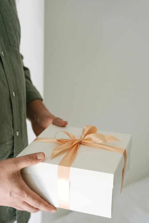 a man holding a white box with a brown ribbon, pexels contest winner, award - winning crisp details, sleek design, pastel', gifts