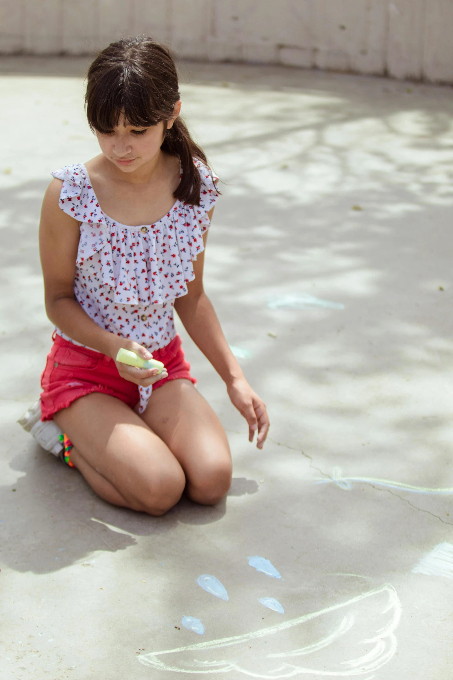 a little girl sitting on the ground drawing with chalk, by Lilia Alvarado, unsplash, sun dappled, teenage girl, fluorescent spots, hispanic